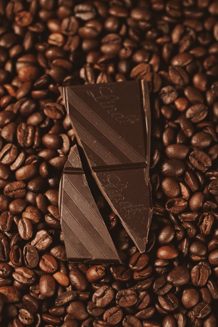 Top view of dark chocolate on freshly roasted coffee beans, perfect for food enthusiasts.
