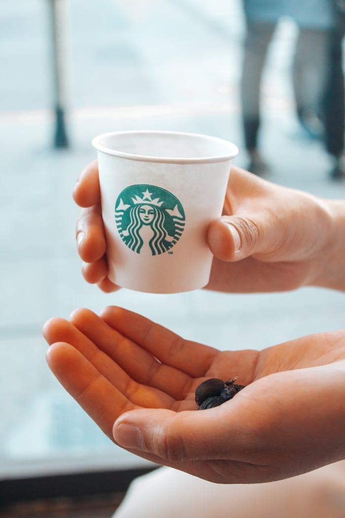 Hand holds a Starbucks cup and coffee beans, symbolizing coffee culture in Buenos Aires.